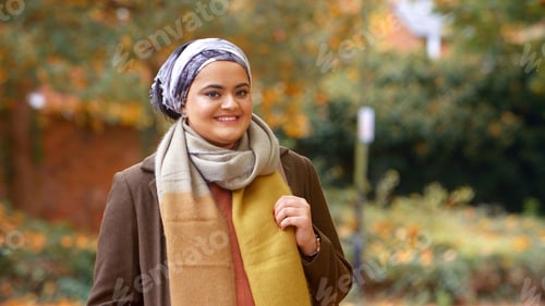 Preview: Portrait Of Smiling Young British Muslim Woman Wearing Headscarf In Autumn Park