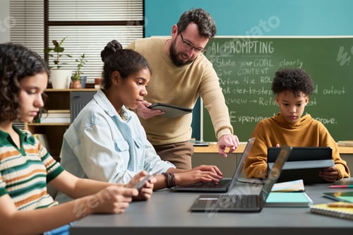 Preview: Caucasian Man Supervising Multiethnic Teenagers Working on Laptops