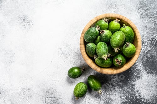 Preview: Green feijoa fruits in a wooden plate on a grey background.