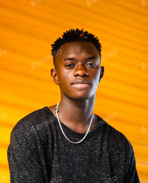 Preview: Shallow focus shot of a young black male on a yellow wall background