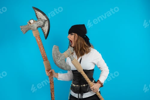 Preview: Angry young pirate holding war axes and screaming on blue background