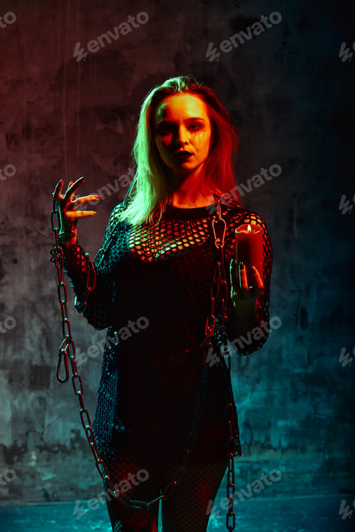 Preview: close up portrait of beautiful sexy witch with halloween makeup. red and black face painting. chain