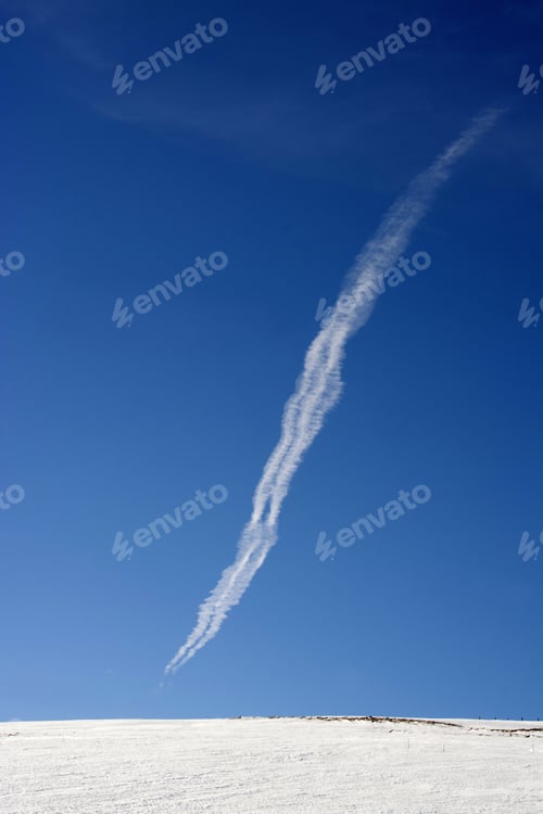 Preview: Vertical shot of vapor trail of an airplane in the blue sky