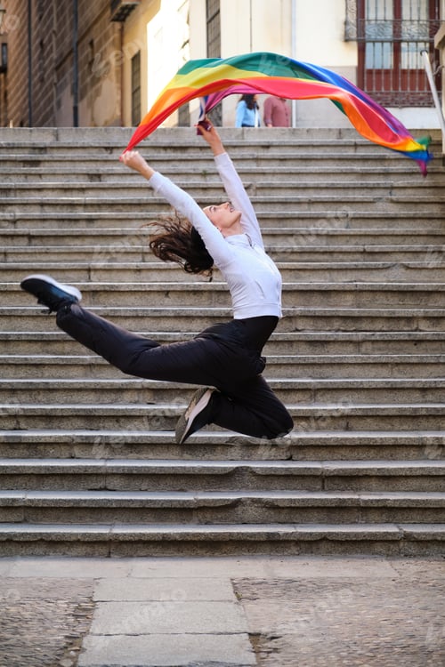 Preview: Woman jumping on stairs holding rainbow flag representing freedom