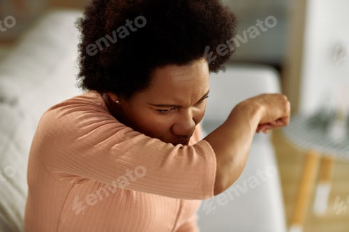Preview: African American Woman Coughing Into Her Elbow At Home.