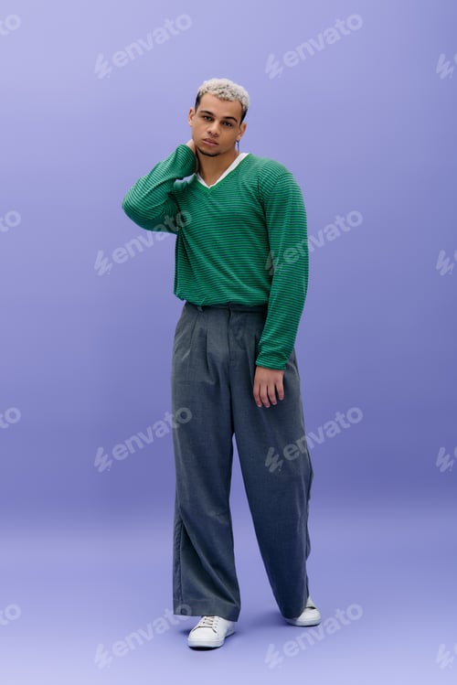 Preview: Young man with dyed hair poses in front of a vibrant purple backdrop