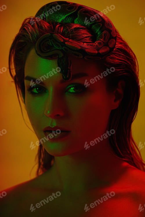 Preview: Stunning woman in a mix of red and green light, with a python snake gracefully positioned on her hea