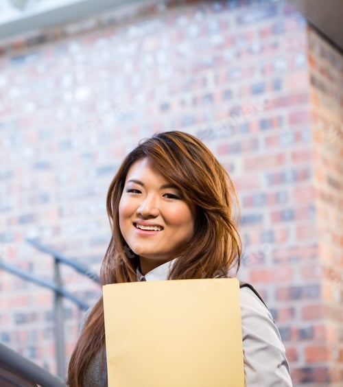 Preview: Smiling Asian woman holding folder, standing confidently in office hallway