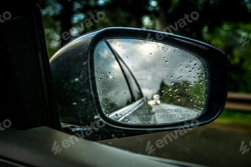 Vorschau: Blick in einen Rückspiegel an einem Regentag beim Fahren auf einer Autobahn