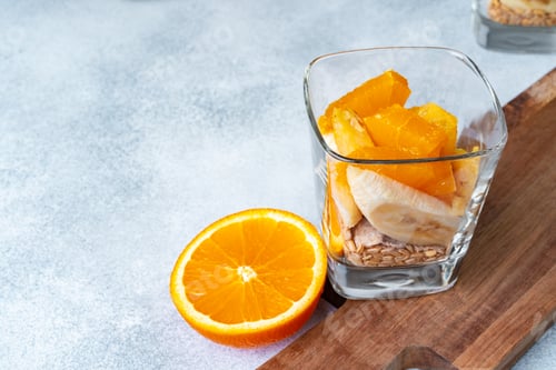 Preview: Glass with fruit pieces and oatmeal muesli on wooden board
