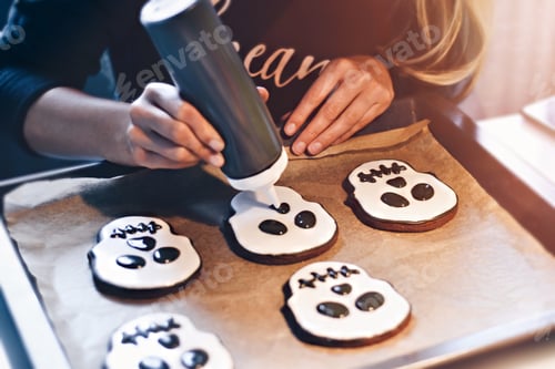 Preview: Cropped shot of woman decorating Halloween cookies