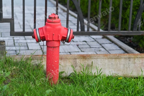 Preview: A red fire hydrant near an iron fence.