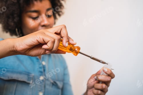 Preview: Afro woman fixing something with a screwdriver.