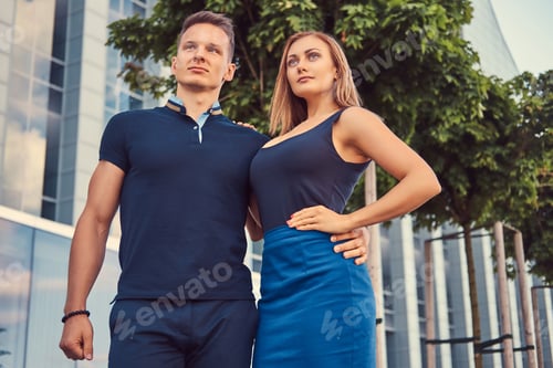Preview: Attractive fashionable couple standing in the modern city against a skyscraper.