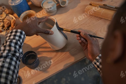 Preview: Ceramic artist painting exterior surface of pottery piece