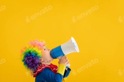 Preview: Funny kid clown playing against yellow background