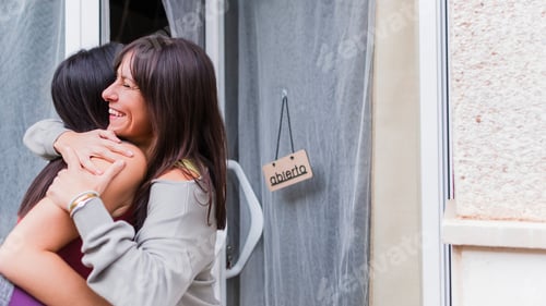 Vista previa: Amigos hispanos y felices abrazándose frente a la entrada del estudio de yoga
