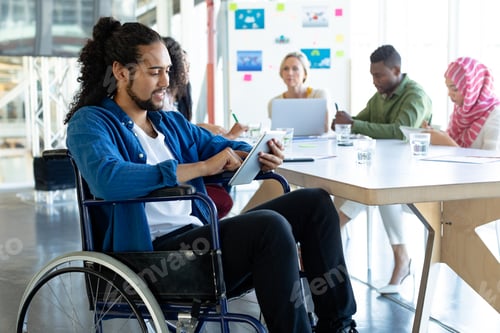 Preview: Mixed-race disabled businessman using digital tablet in conference room during meeting