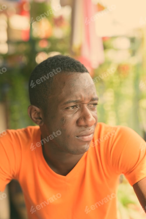 Vista previa: Face of young black African man thinking while looking at distance in the peaceful garden outdoors