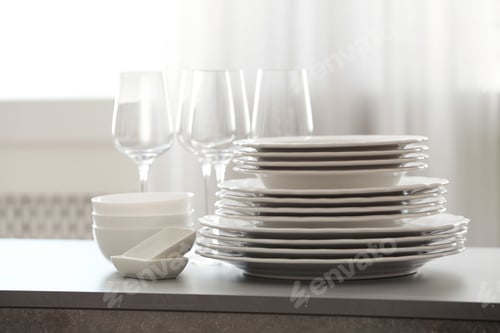 Preview: Set of clean dishware and wineglasses on table indoors
