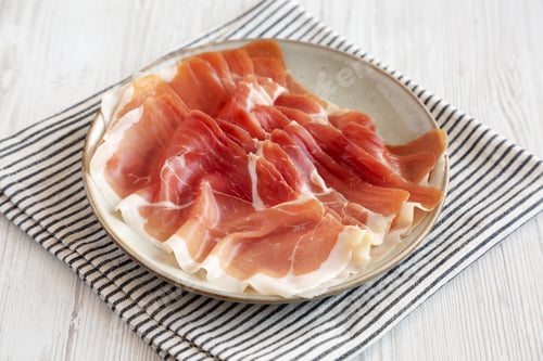 Preview: Sliced Prosciutto Ham on a Plate, side view.