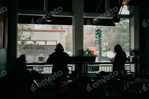 Preview: View looking outside a coffee shop window dark moody winter strangers studying reading using phones