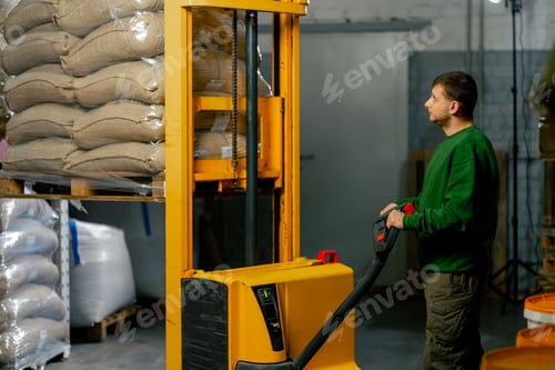 Preview: a worker at coffee factory uses a yellow forklift to lower bags of coffee