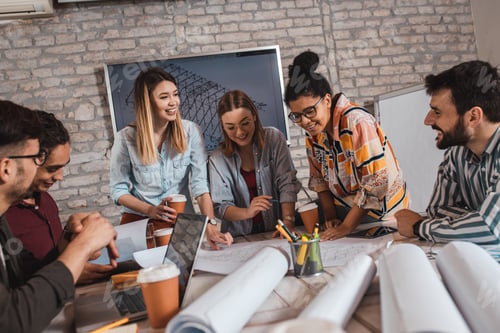 Preview: Group of modern business people in casual wear discussing architectural designs in office.