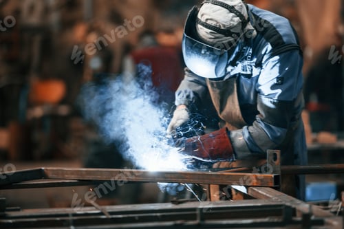 Preview: Close up view. Factory worker in protective mask is welding the iron