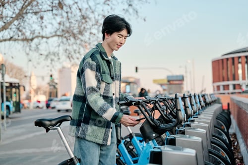Preview: Young stylish man using bicycle rent mobile app,