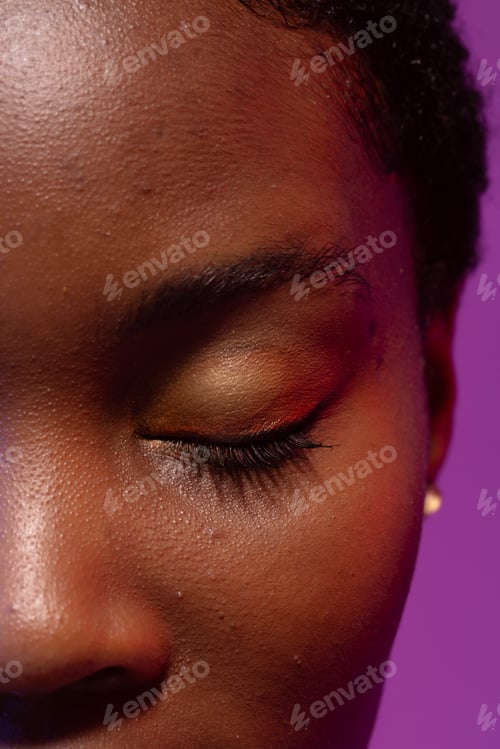 Preview: Close up of closed eye of african american woman with short hair on purple background