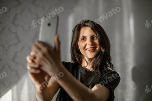Preview: young beautiful girl takes a selfie on her smartphone