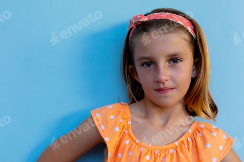 Preview: Happy caucasian schoolgirl with band over blue background at elementary school, copy space