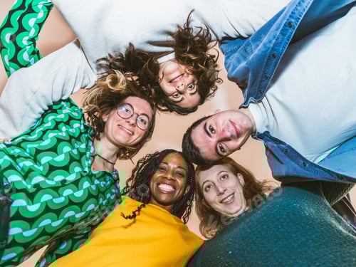 Visualização: Grupo multicultural de jovens profissionais sorrindo em um círculo de trabalho em equipe