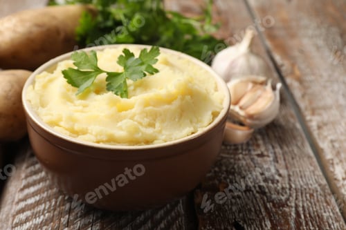 Vista previa: Delicioso puré de patatas con perejil y ajo sobre mesa de madera, primer plano. Espacio para texto