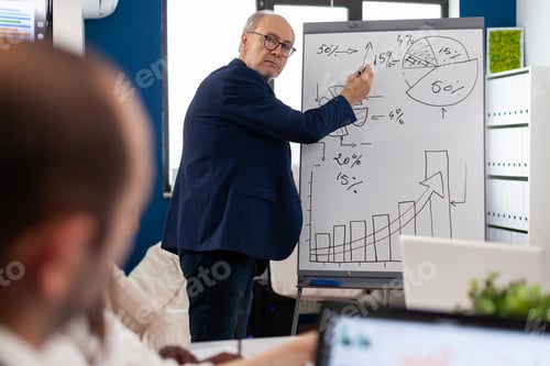 Preview: Elderly businessman giving presentation to multiethnic team