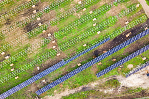 Preview: Aerial view of solar power plant under construction on green field. Assembling of electric panels