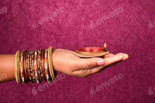 Preview: Female hand holding lit earthen lamp at Diwali festival in India