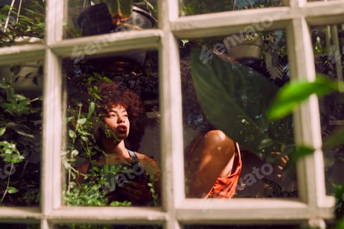 Preview: Black women, happy and talking with plants, garden and vegetation in greenhouse. African American f