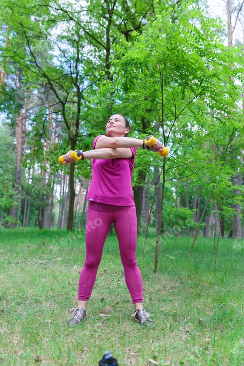 Preview: Active Woman Exercising with Weights in a Forest