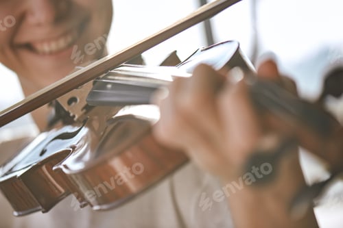 Preview: Enjoying classical music. Close up view of smiling violinist playing classical music on the brown
