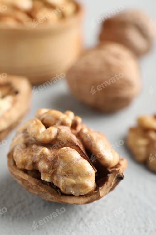Preview: Fresh walnuts with shells on gray table, closeup