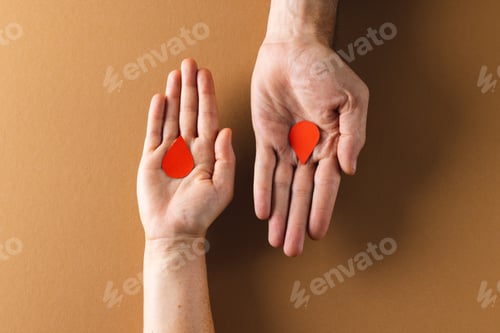 Preview: Hands of caucasian woman and man holding blood drops, on brown background
