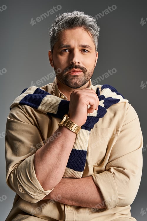 Preview: Stylish man with bristle in fashionable outfit poses confidently in studio setting