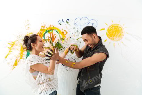 Preview: Couple with hands dirty in paints laughing and having fun