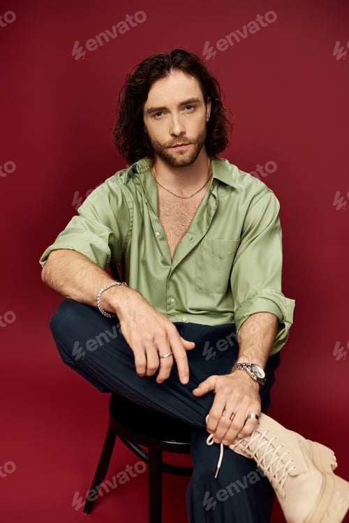 Preview: The enigmatic elegance: man in green shirt on chair