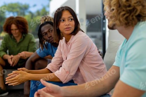 Preview: Group of diverse people sitting on sofa and talking in group therapy session