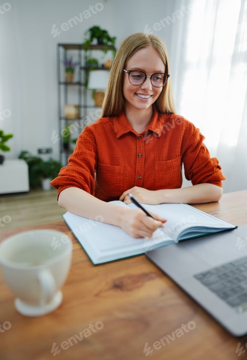 Preview: Writing in a notebook while enjoying a cozy home workspace