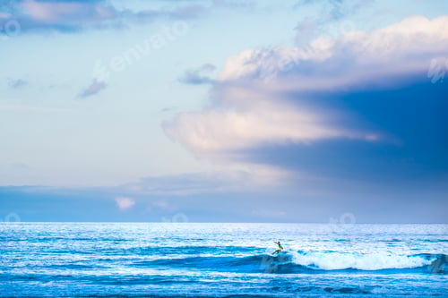 Preview: Surfer tourist athlete do surf water sport activity alone in the blue ocean waves - colorful sky
