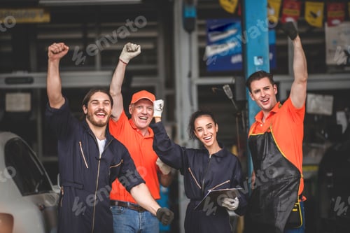 Preview: Group of young and senior car mechanics in garage wearing uniform enjoying and celebrating